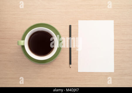 A green cup of coffee on the background of a table and a white sheet of paper simulates the beginning and pencil Stock Photo