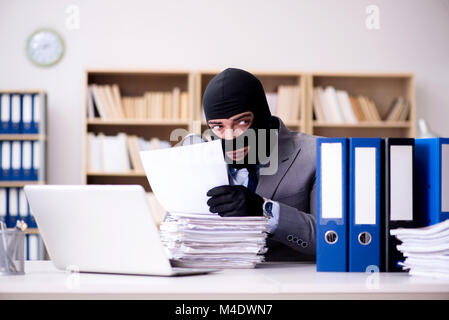 Criminal businessman wearing balaclava in office Stock Photo