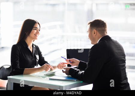 Businesspeople man and woman sitting at a table and signing a contract at office Stock Photo