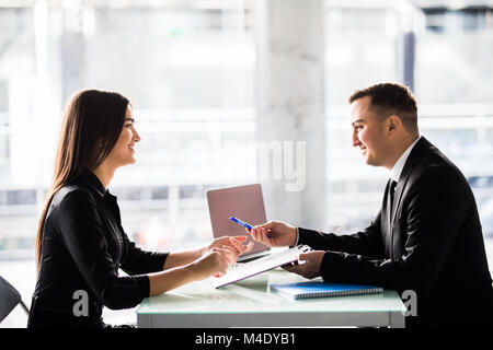 Businesspeople man and woman sitting at a table and signing a contract at office Stock Photo