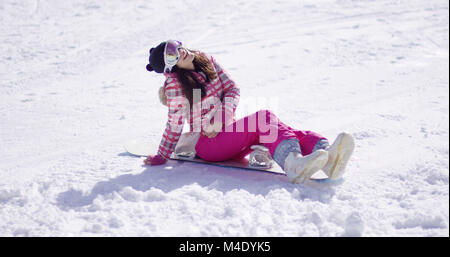 Happy young woman sat on snowboard Stock Photo