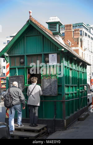 Colour Photograph of two people being served food and drink at a cabbies green hut in Wellington Place, London, England, UK. Credit: London Snapper Stock Photo