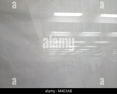 Abstract white background: on the left side is a white coarse paper under the glass. in the right part of the glass are reflected the lamps and the wa Stock Photo
