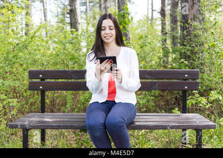 Attractive young woman with e-book/tablet in the park Stock Photo