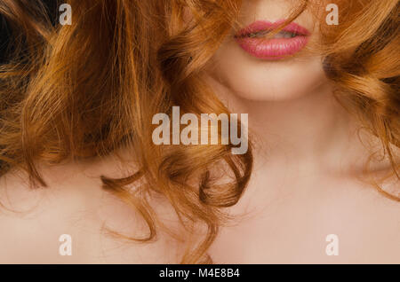 Beautiful curly long red hair on the face of woman Stock Photo