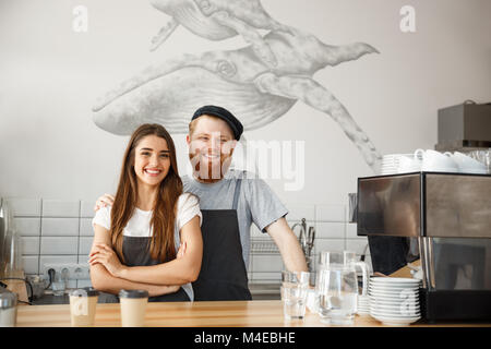 Coffee Business Concept - Positive young bearded man and beautiful attractive lady barista couple enjoy working together at the modern coffee shop Stock Photo