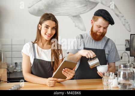 Coffee Business Concept - happy young couple business owners of small coffee shop working and planing on tablet. Stock Photo