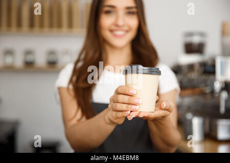 Coffee Business Concept - Beautiful Caucasian lady smiling at camera offers disposable take away hot coffee at the modern coffee shop Stock Photo