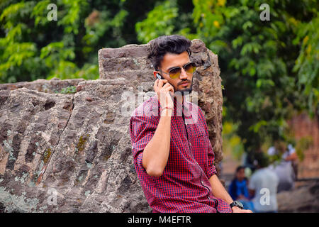 Young man with checked shirt looking at cell phone, Pune, Maharashtra. Stock Photo