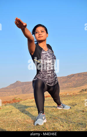 Young Indian girl doing fitness exercises with mountain backdrop, Pune, Maharashtra. Stock Photo