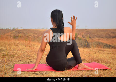 Young Indian girl doing Yoga . Vrikshasana with mountain backdrop