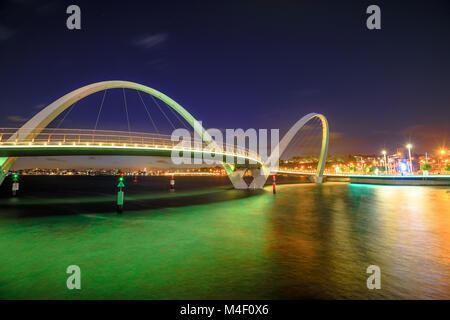 Elizabeth Quay Bridge by night on Swan River at entrance of Elizabeth Quay marina. The arched pedestrian bridge is a tourist attraction in Perth, Western Australia. Copy space. Stock Photo