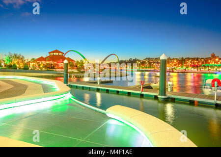 Walkway with night lighting at popular tourist attraction Elizabeth Quay Marina. The iconic Elizabeth Quay Bridge on Swan River illuminated at blue hour. Perth Waterfront Cityscape, WA. Copy space. Stock Photo