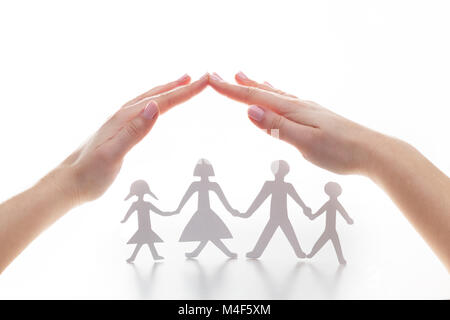 Paper family under hands in gesture of protection. Stock Photo