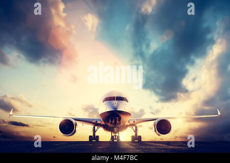 Passenger airplane taking off on runway at sunset Stock Photo