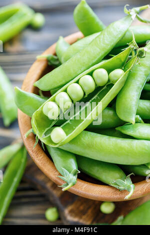 Pods sweet green peas in bowl closeup. Stock Photo