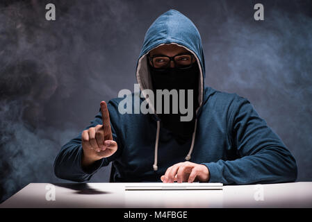 Computer hacker working in dark room Stock Photo