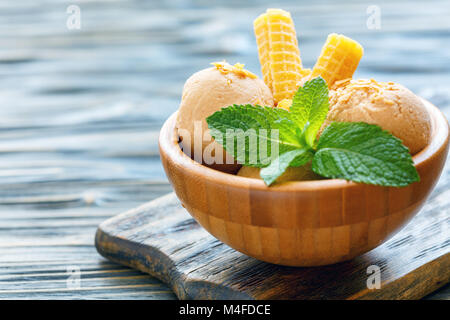 Caramel ice cream and crispy waffles in a wooden bowl. Stock Photo