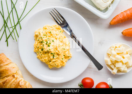 fresh scrambled eggs on white plate on breakfast table Stock Photo