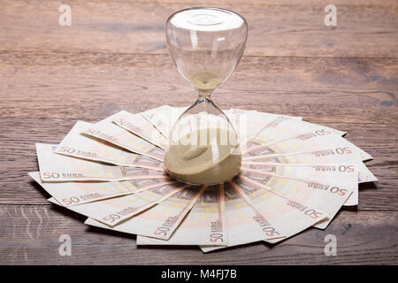 Close-up Of An Hourglass On Euro Notes At Wooden Desk Stock Photo