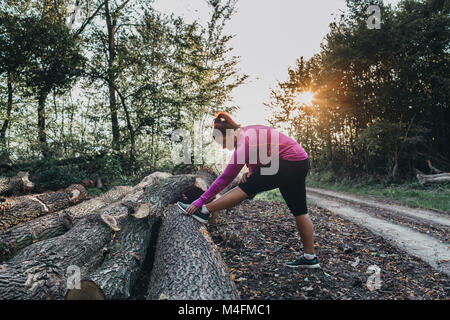 Portrait of a female jogger getting ready for a jog and doing some stretches in a forest. Stock Photo