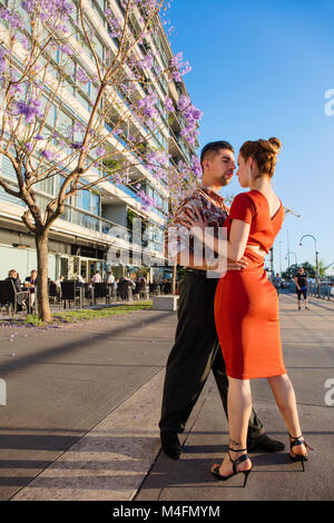 A couple dancing tango in Puerto Madero on springtime, with Jacaranda trees in the background. Buenos Aires, Argentina. Stock Photo