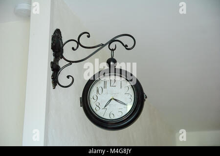 Round Metal Vintage Clock on White Wall. The Arrows Show 7:20. Stock Photo