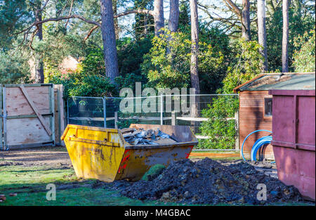 Real estate construction site: full yellow skip on a building site filled with demolition waste from a residential house property before redevelopment Stock Photo