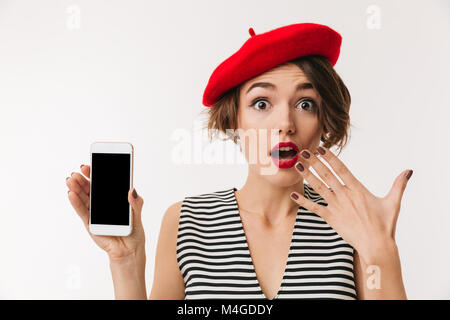 Portrait of a surprised woman wearing red beret showing blank screen mobile phone isolated over white background Stock Photo