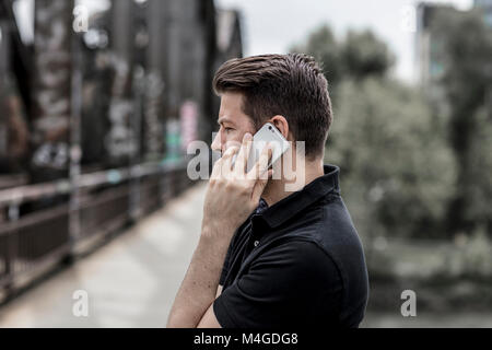 Profile of a man talking on a mobile phone with an urban background. Stock Photo