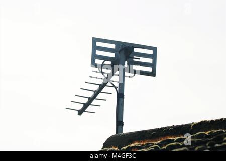 TV aerial on gable end of a moss covered tiled roof Stock Photo