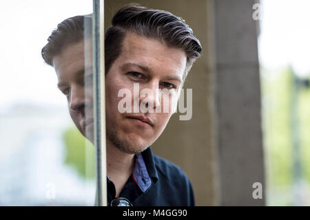 Man posing in front of glass window reflecting his image. Close up. Stock Photo