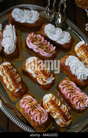 Wedding variety cakes decorated with whipped cream on a silver tray - candy bar, tasty buffet Stock Photo