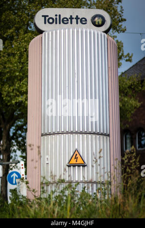 Public toilette on the street with high voltage signs in daytime, in Germany, Europe, shot 2017 Stock Photo