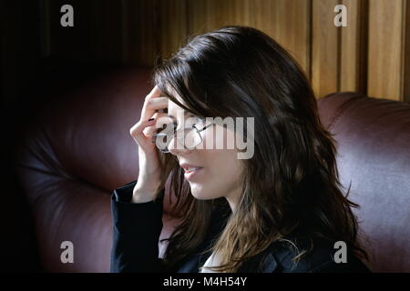 The girl in a suit sits on  leather sofa Stock Photo