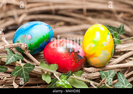 Three colorful hen eggs in a natural nest Stock Photo