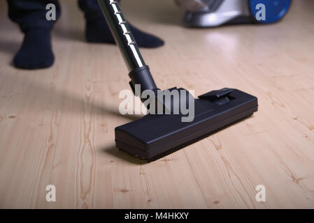 Man vacuums the floor, focus on the foreground Stock Photo
