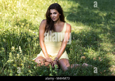Young woman in summer dress is lying on meadow Stock Photo