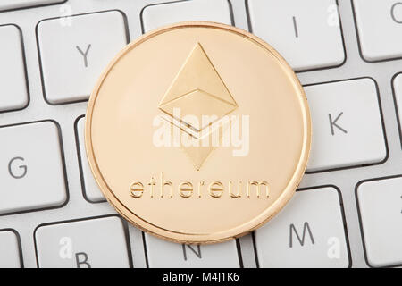 Ethereum golden cryptocurrency coin on keyboard Stock Photo