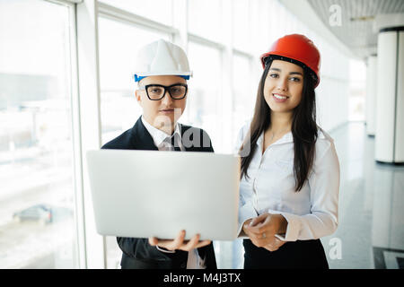 Engineers working on a building site holding laptop, architect man working with engineer women inspection in workplace for architectural plan Stock Photo