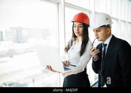 Engineers working on a building site holding laptop, architect man working with engineer women inspection in workplace for architectural plan