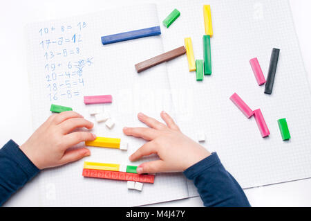 Open exercise book with colored plastic number rods on white background. Stock Photo