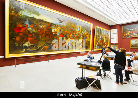 France, Paris, The Louvre Museum. A teacher conducts an art class among the renaissance-styled art pieces. This giant painting nearly covers the wall. Stock Photo