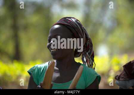 A Mandinka (Mandingo) woman smiles while she dances and plays traditional, ceremonial music in Bintang village, The Gambia, West Africa. Stock Photo