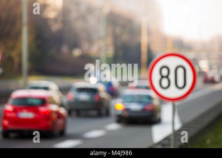 Defocused image of traffic sign showing 80 km/h speed limit on a highway full of cars Stock Photo