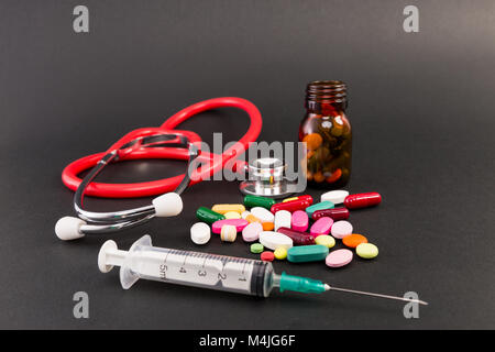Pills capsules syringe and stethoscope on dark background Stock Photo