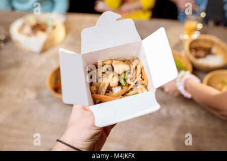 Holding a box with asian food indoors Stock Photo