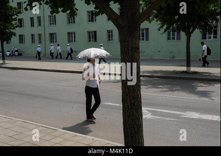 08.08.2012, Pyongyang, North Korea, Asia - A pedestrian with an umbrella walks down a road in central Pyongyang. Stock Photo