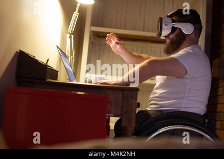Disabled man in virtual reality headset using laptop Stock Photo