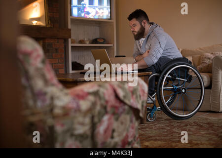 Disabled man using laptop at home Stock Photo